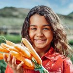 little girl with carrots in her hands