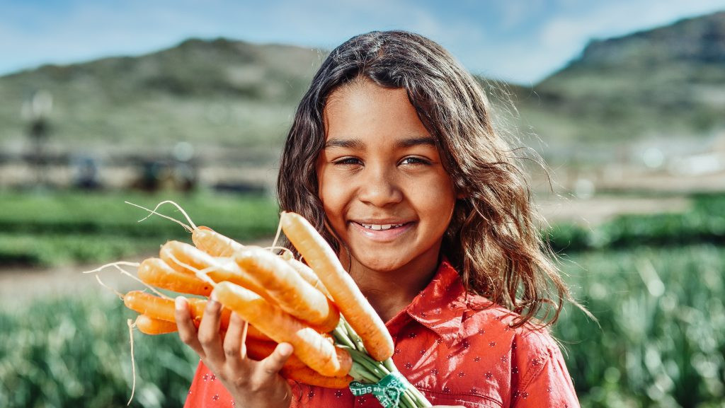 little girl with carrots in her hands