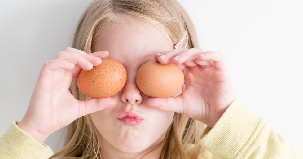 child holding two eggs in front of eyes