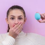 woman in white sweater holding blue egg
