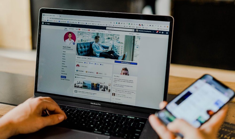 person using both phone and laptop for facebook